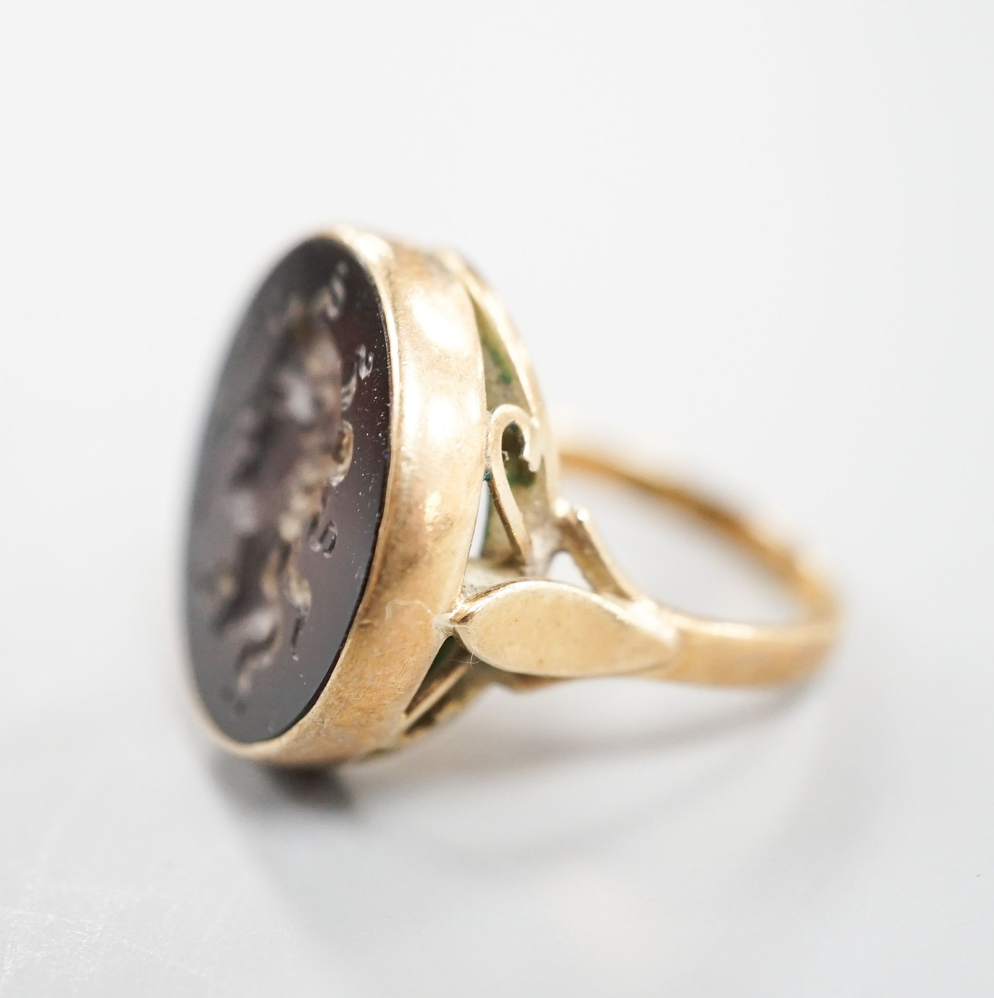 An early 20th century 9ct and intaglio brown chalcedony set ring, carved with the bust of a lady to dexter, size Q, gross weight 8.4 grams.